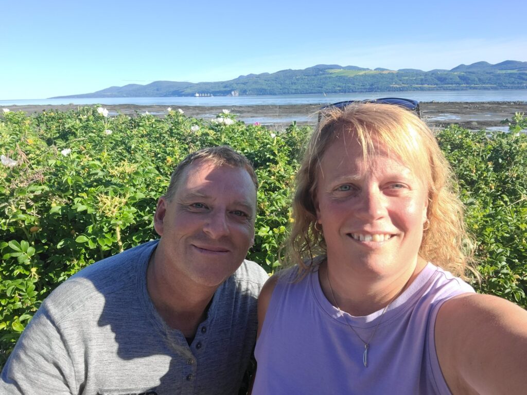 Nathalie et Christian devant les rosiers sauvages et le fleuve à La Malbaie